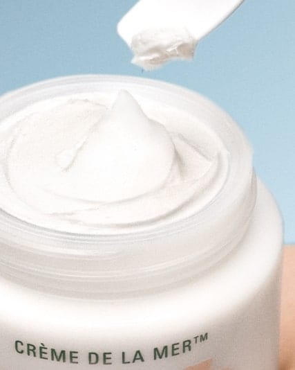 Photograph of small amount of creme de la mer being removed from canister with applicator.